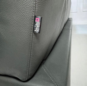 Gebrauchtes graues Brühl Moule Designer Leder Sofa vor einer Wand, stilvoll und modern eingerichtet.