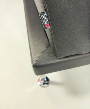 Gebrauchtes graues Brühl Moule Small Designer Leder Sofa vor einer Wand, stilvoll und modern eingerichtet.
