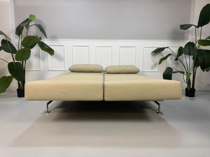 Gebrauchtes Designer Stoff Sofa vor einer Wand, stilvoll und modern eingerichtet.