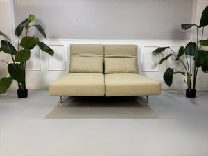 Gebrauchtes Designer Stoff Sofa vor einer Wand, stilvoll und modern eingerichtet.