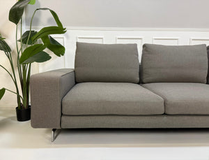 Erneuertes graues Minotti Sherman Designer Stoff Sofa vor einer Wand, stilvoll und modern eingerichtet.