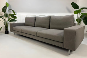 Erneuertes graues Minotti Sherman Designer Stoff Sofa vor einer Wand, stilvoll und modern eingerichtet.