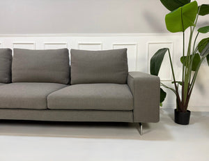 Erneuertes graues Minotti Sherman Designer Stoff Sofa vor einer Wand, stilvoll und modern eingerichtet.