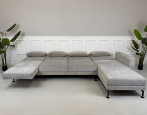 Graues Ausstellungsstück Brühl Moule Designer Stoff Sofa vor einer Wand, stilvoll und modern eingerichtet.