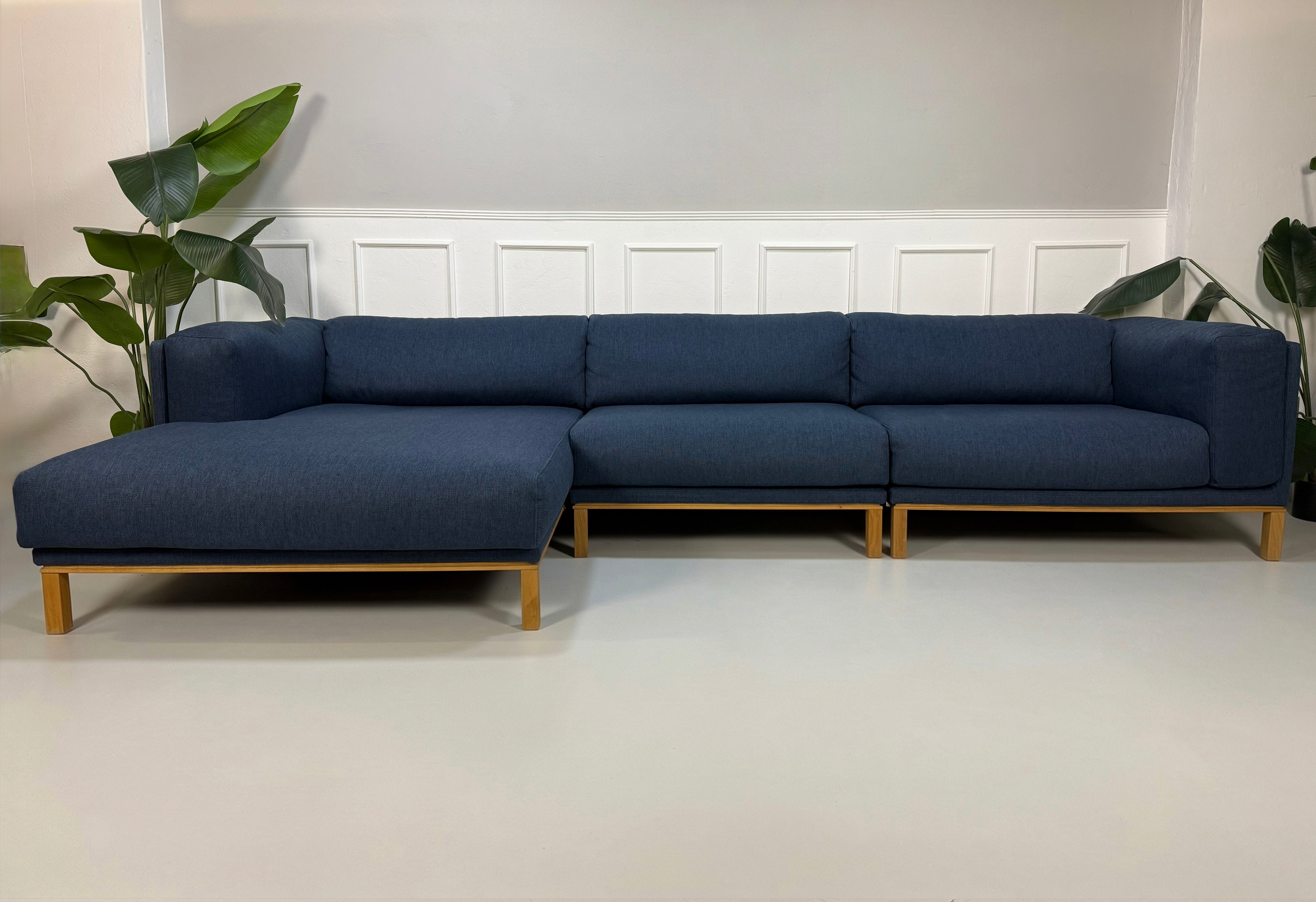 Gebrauchtes blaues Bolia Cosy Designer Stoff Sofa vor einer Wand, stilvoll und modern eingerichtet.