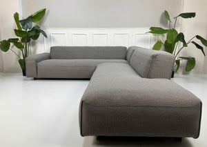 Erneuertes graues Rolf Benz Mio Designer Stoff Sofa vor einer Wand, stilvoll und modern eingerichtet.