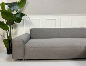 Erneuertes graues Rolf Benz Mio Designer Stoff Sofa vor einer Wand, stilvoll und modern eingerichtet.