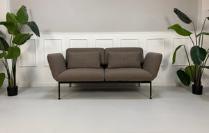 Ausstellungsstück Brühl Roro in braun Designer Stoff Sofa vor einer Wand, stilvoll und modern eingerichtet.
