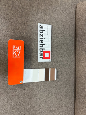 Ausstellungsstück Brühl Roro in braun Designer Stoff Sofa vor einer Wand, stilvoll und modern eingerichtet.