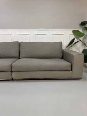 Gebrauchtes graues Minotti Hamilton Designer Stoff Sofa vor einer Wand, stilvoll und modern eingerichtet.