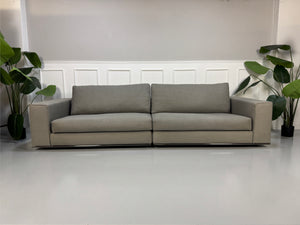 Gebrauchtes graues Minotti Hamilton Designer Stoff Sofa vor einer Wand, stilvoll und modern eingerichtet.