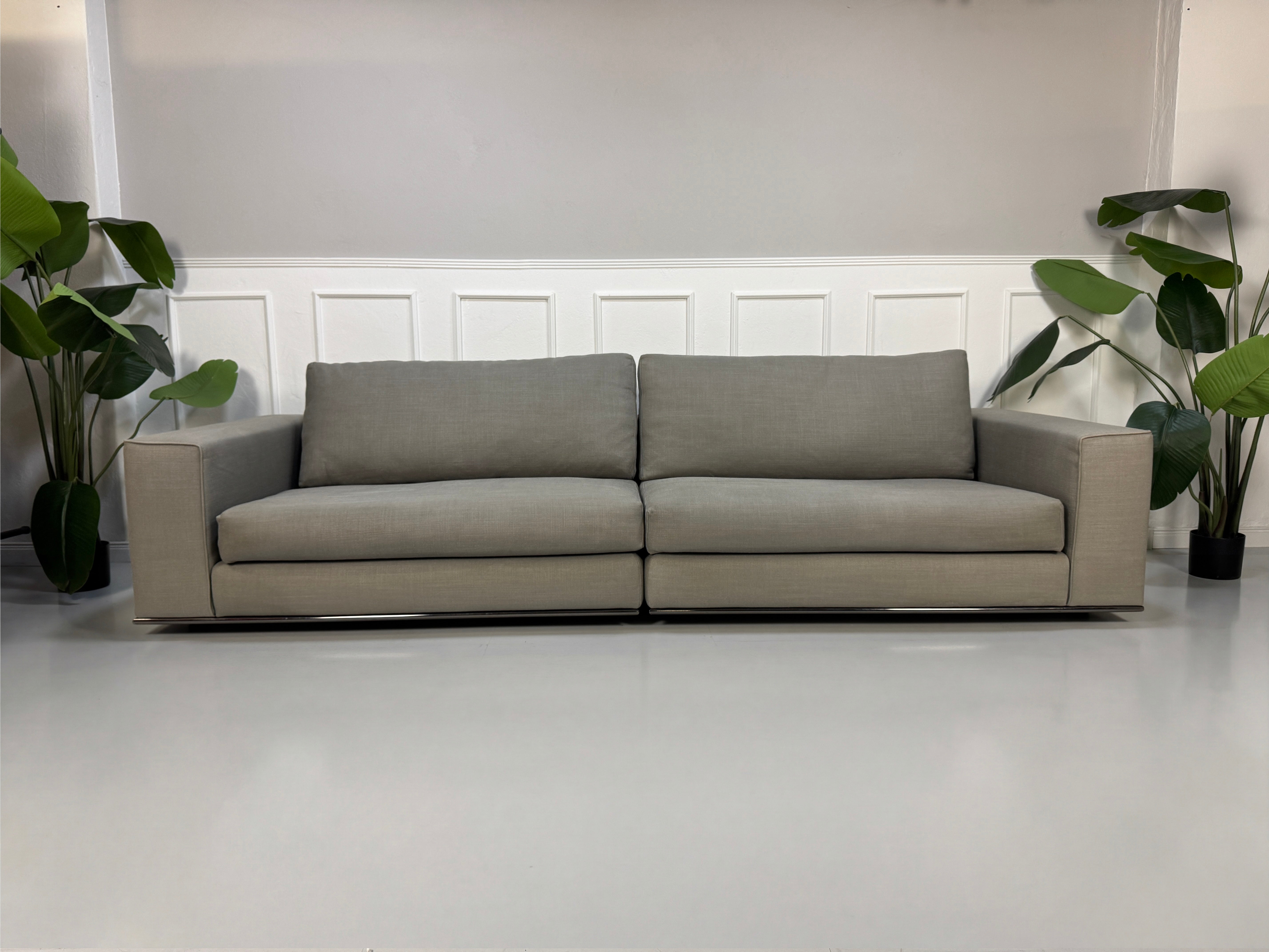 Gebrauchtes graues Minotti Hamilton Designer Stoff Sofa vor einer Wand, stilvoll und modern eingerichtet.