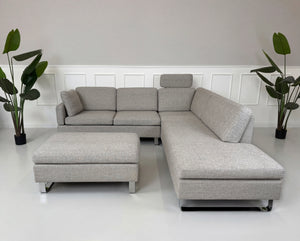 Gebrauchtes graues Brühl Alba Designer Stoff Sofa vor einer Wand, stilvoll und modern eingerichtet
