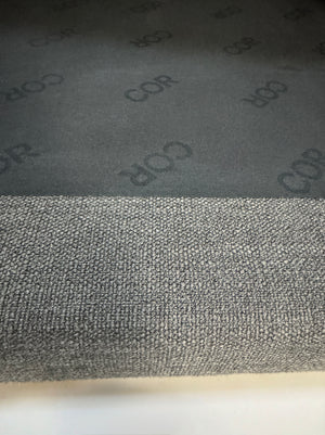 Gebrauchtes graues COR Pilotis Designer Stoff Sofa vor einer Wand, stilvoll und modern eingerichtet.