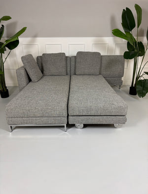 Gebrauchtes graues Brühl Four Two Designer Stoff Sofa vor einer Wand, stilvoll und modern eingerichtet.