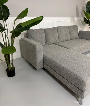 Gebrauchtes graues Brühl Four Two Designer Stoff Sofa vor einer Wand, stilvoll und modern eingerichtet.