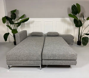 Gebrauchtes graues Brühl Four Two Designer Stoff Sofa vor einer Wand, stilvoll und modern eingerichtet.