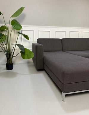 Gebrauchtes grau blaues Brühl Four Two Designer Stoff Sofa vor einer Wand, stilvoll und modern eingerichtet.