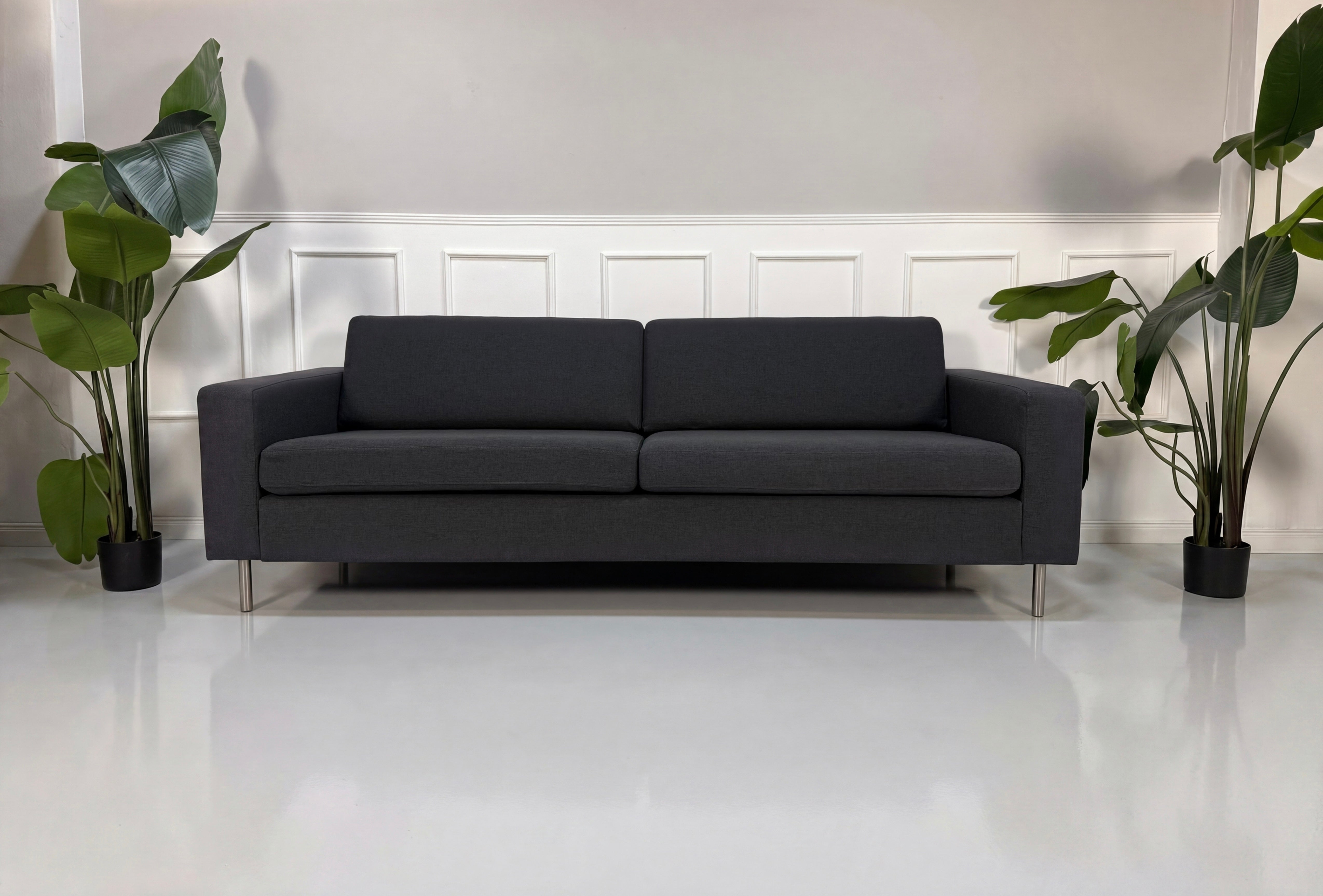 Gebrauchtes graues Bolia Scandinavia Designer Stoff Sofa vor einer Wand, stilvoll und modern eingerichtet.