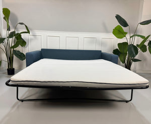 Gebrauchtes blaues Bolia Scandinavia Designer Stoff Sofa vor einer Wand, stilvoll und modern eingerichtet.