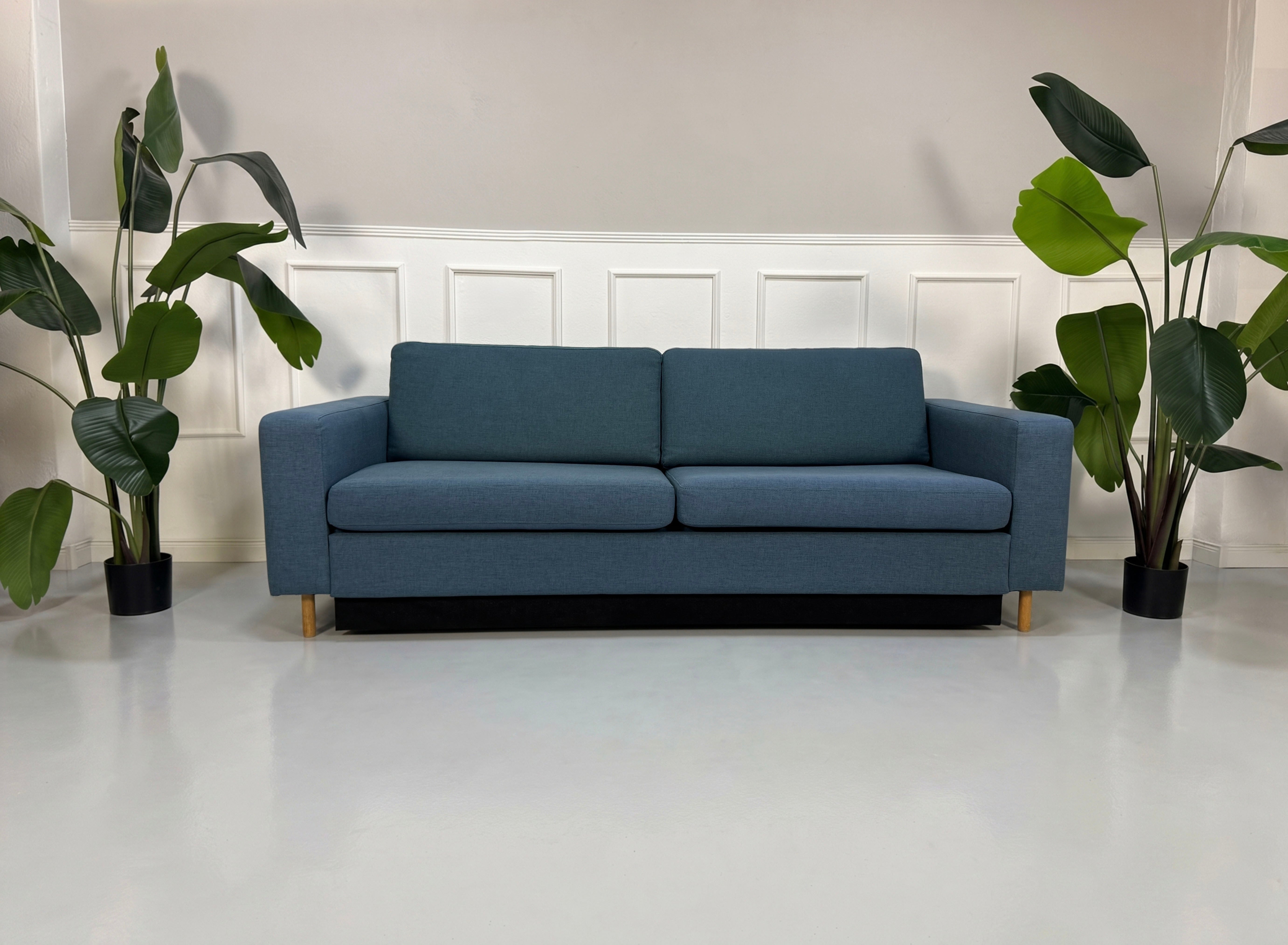 Gebrauchtes blaues Bolia Scandinavia Designer Stoff Sofa vor einer Wand, stilvoll und modern eingerichtet.