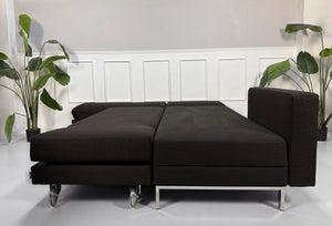 Gebrauchtes braunes Brühl Fourtwo Designer Stoff Sofa mit Hocker vor einer Wand, stilvoll und modern eingerichtet.
