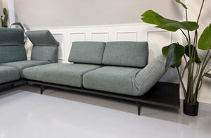 Gebrauchtes blau graues Rolf Benz Aura Designer Stoff Sofa vor einer Wand, stilvoll und modern eingerichtet.