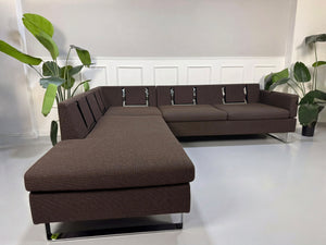 Gebrauchtes braunes Brühl Ecksofa Designer Stoff Sofa vor einer Wand, stilvoll und modern eingerichtet.