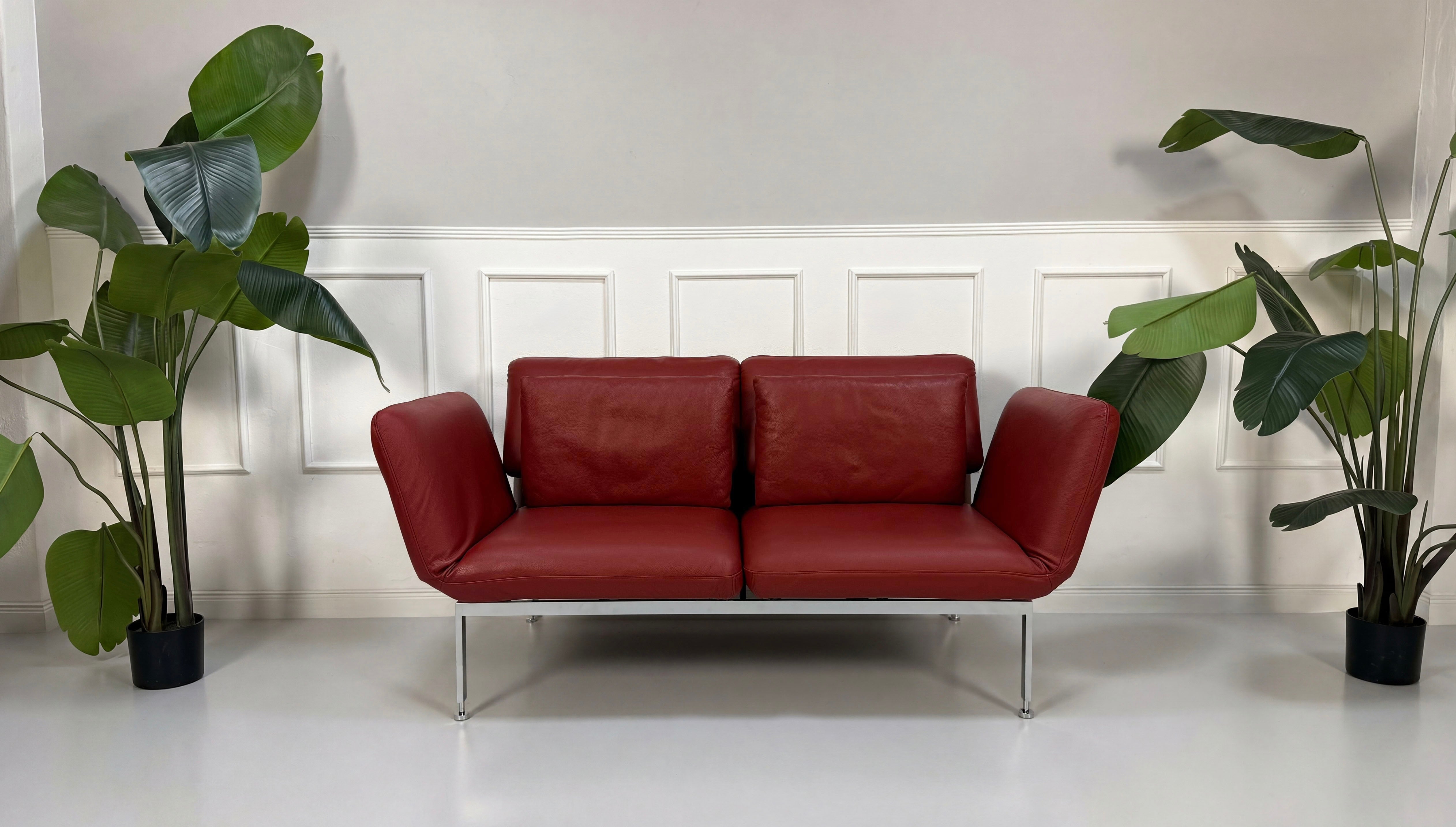 Gebrauchtes rotes Brühl Roro Designer Leder Sofa vor einer Wand, stilvoll und modern eingerichtet.