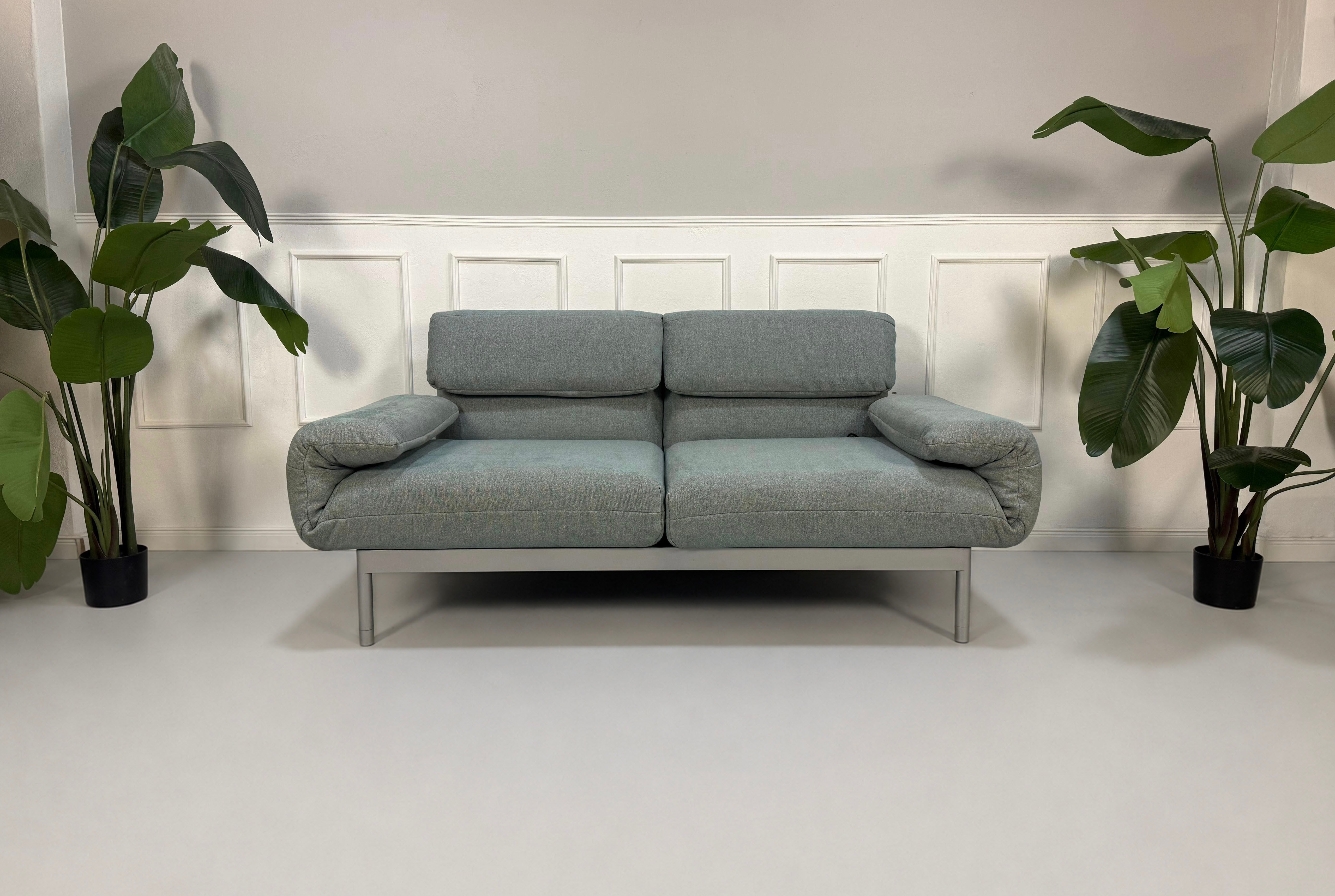 Gebrauchtes graues mint Rolf Benz Plura Designer Stoff Sofa vor einer Wand, stilvoll und modern eingerichtet.