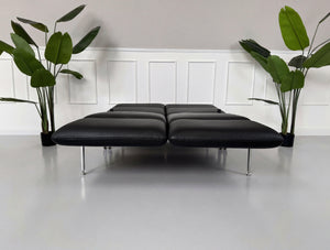Gebrauchtes schwarzes Brühl Roro Small Designer Leder Sofa vor einer Wand, stilvoll und modern eingerichtet.