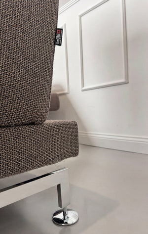 Gebrauchtes braun graues Brühl Moule Designer Stoff Sofa vor einer Wand, stilvoll und modern eingerichtet.