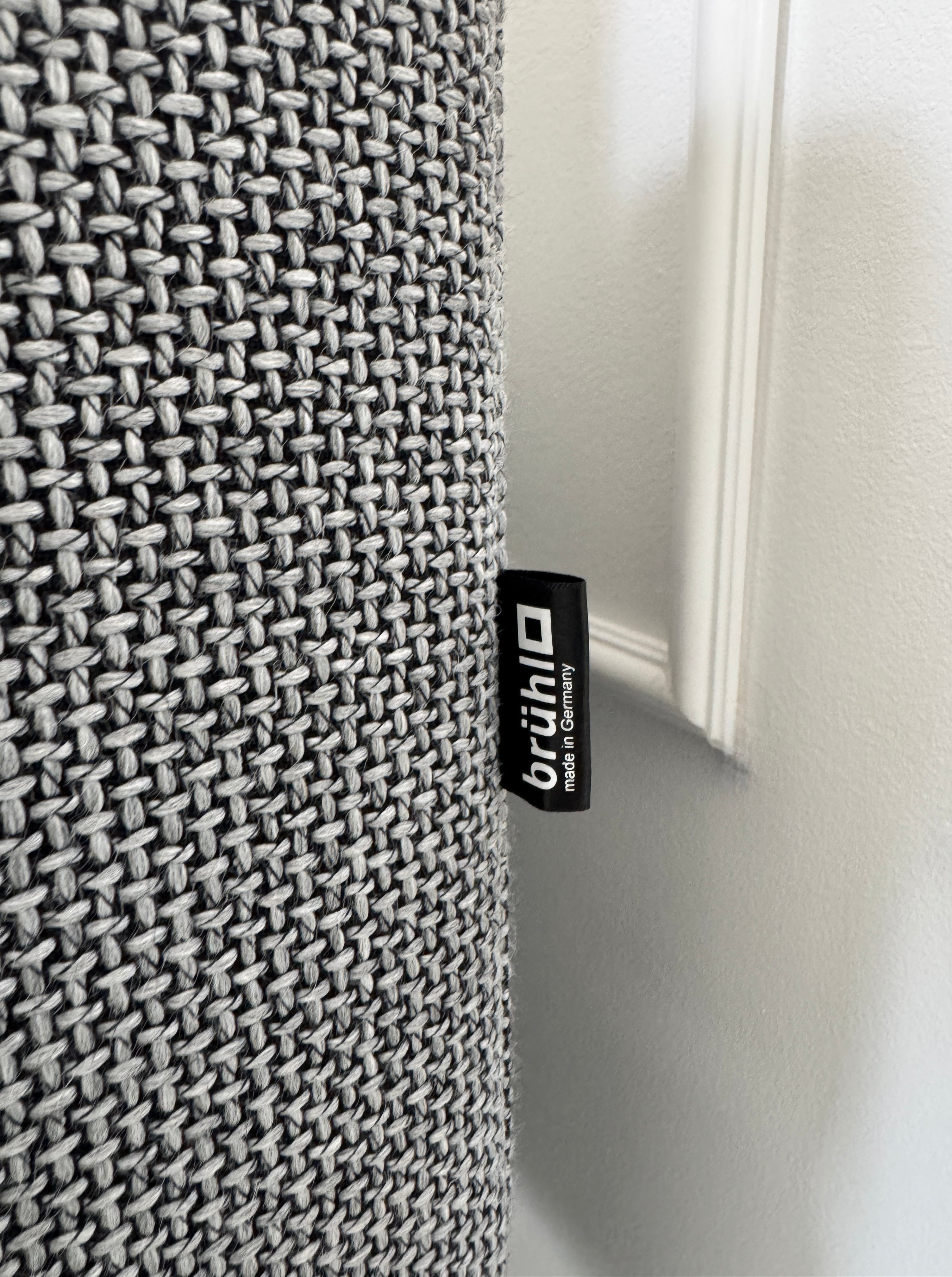 Gebrauchtes graues Brühl Alba Designer Stoff Sofa vor einer Wand, stilvoll und modern eingerichtet.