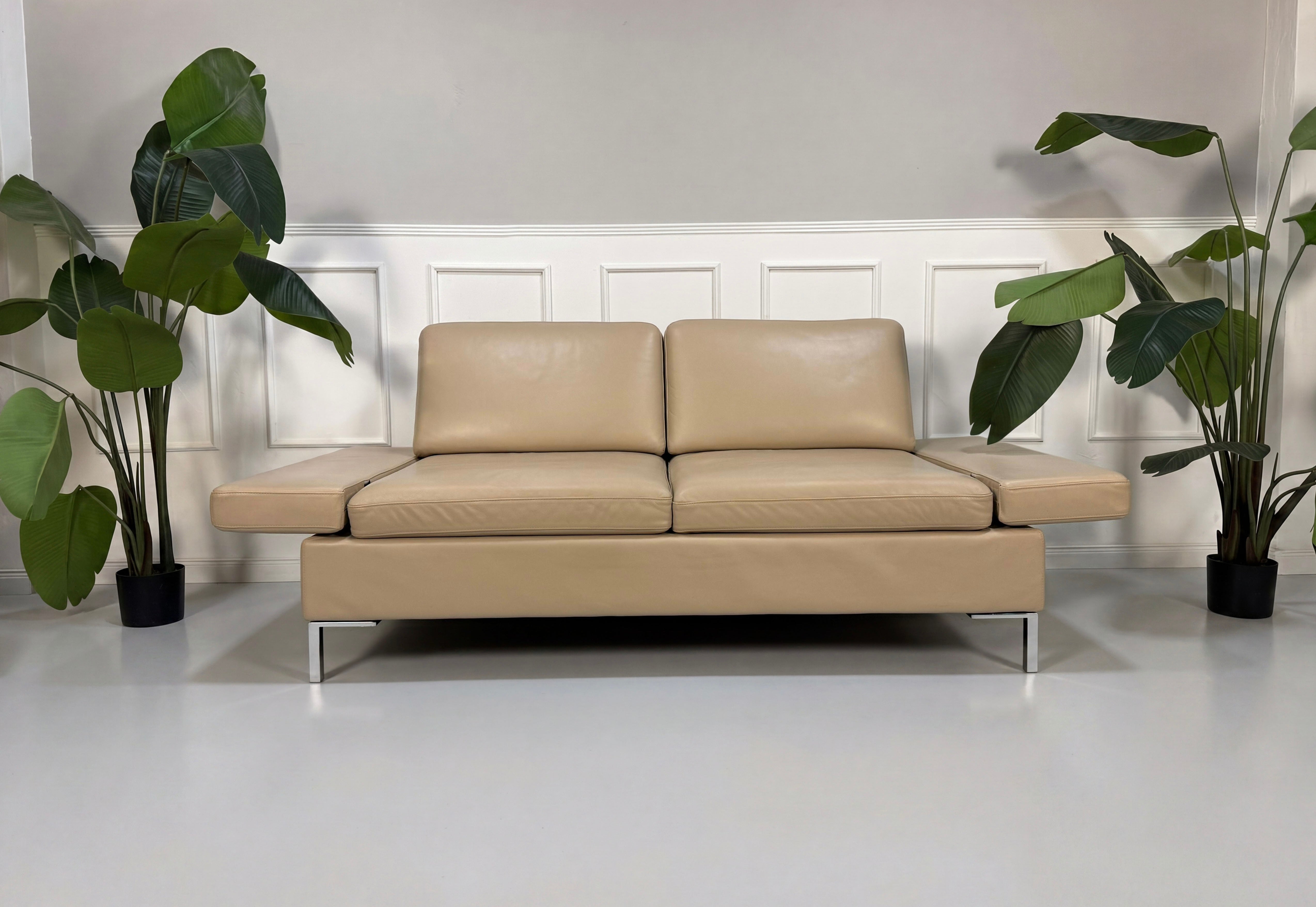 Gebrauchtes beiges Brühl Alba Designer Leder Sofa vor einer Wand, stilvoll und modern eingerichtet.