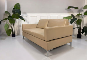 Gebrauchtes beiges Brühl Alba Designer Leder Sofa vor einer Wand, stilvoll und modern eingerichtet.