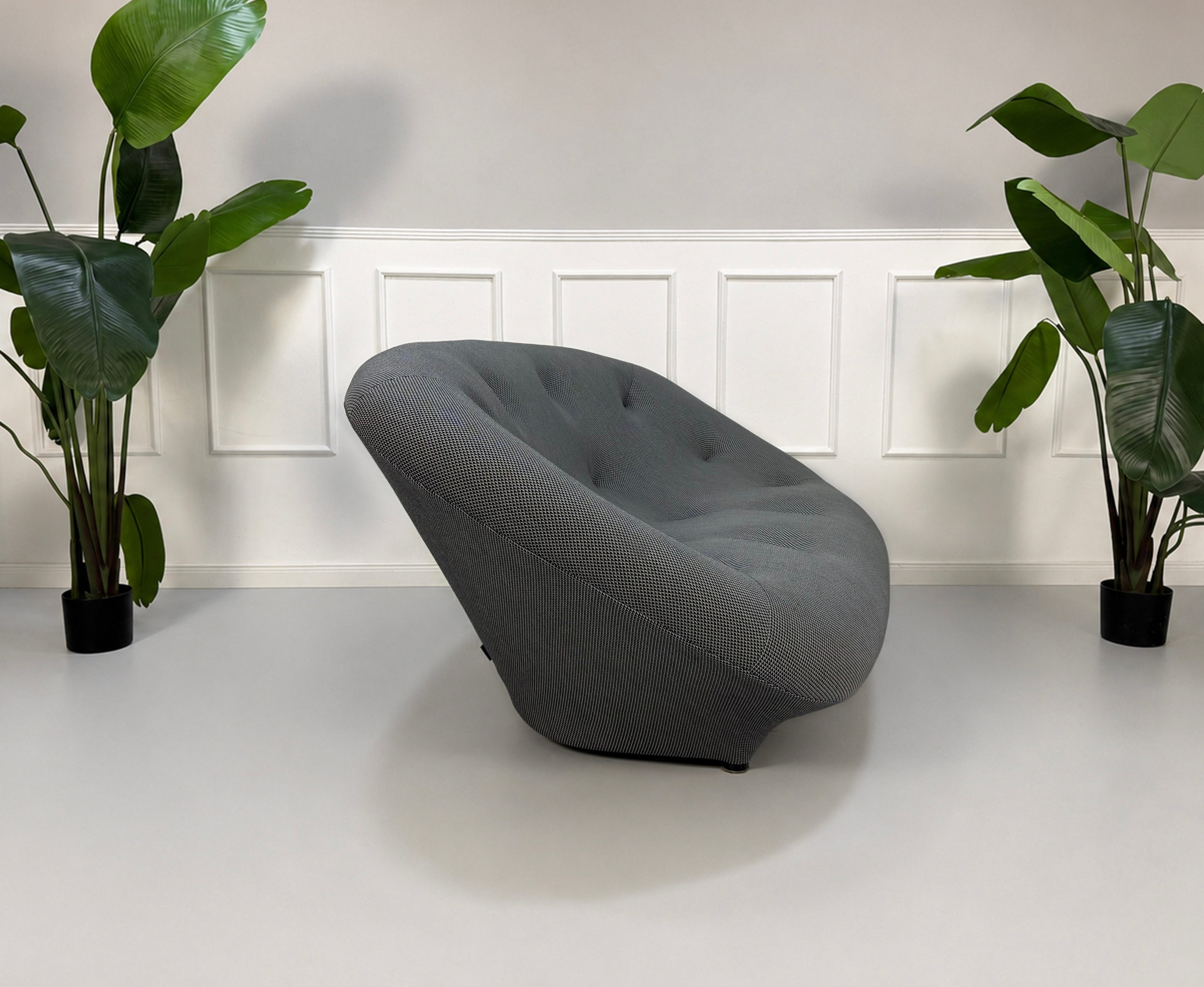 Gebrauchtes graues Ligne Roset Designer Stoff Sofa vor einer Wand, stilvoll und modern eingerichtet.