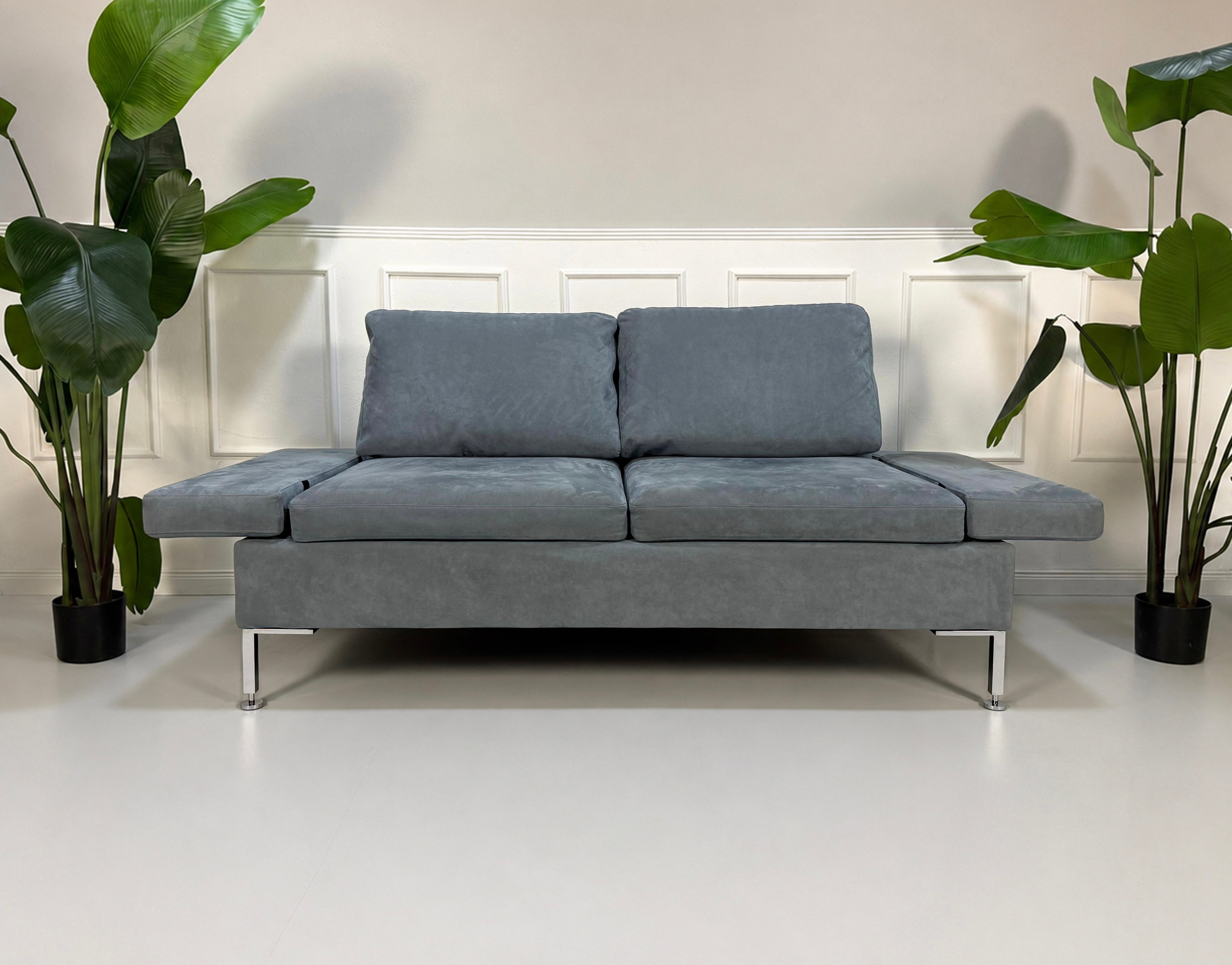 Gebrauchtes blaues Brühl Alba Designer Stoff Sofa vor einer Wand, stilvoll und modern eingerichtet.