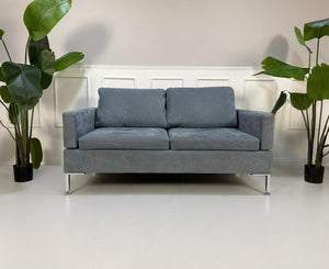 Gebrauchtes blaues Brühl Alba Designer Stoff Sofa vor einer Wand, stilvoll und modern eingerichtet.