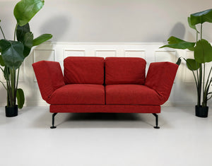 Gebrauchtes rotes Brühl Moule Small Designer Stoff Sofa vor einer Wand, stilvoll und modern eingerichtet.