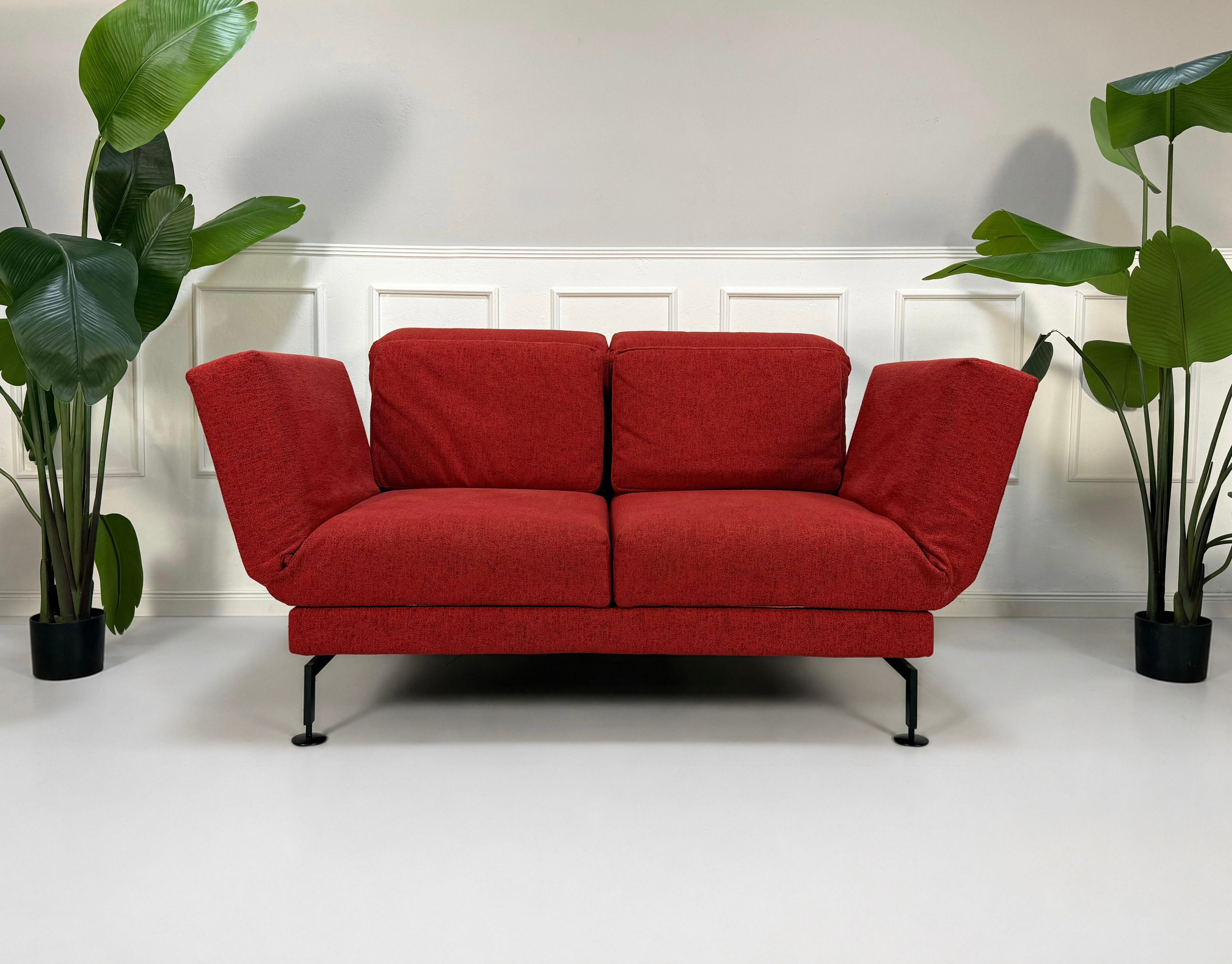 Gebrauchtes rotes Brühl Moule Small Designer Stoff Sofa vor einer Wand, stilvoll und modern eingerichtet.