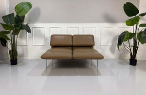 Gebrauchtes braunes Brühl Roro Small Designer Leder Sofa vor einer Wand, stilvoll und modern eingerichtet.