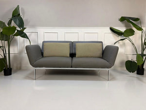 Gebrauchtes graues Brühl Roro Designer Stoff Sofa vor einer Wand, stilvoll und modern eingerichtet.