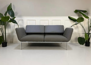 Gebrauchtes graues Brühl Roro Designer Stoff Sofa vor einer Wand, stilvoll und modern eingerichtet.
