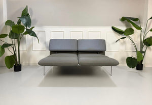 Gebrauchtes graues Brühl Roro Designer Stoff Sofa vor einer Wand, stilvoll und modern eingerichtet.