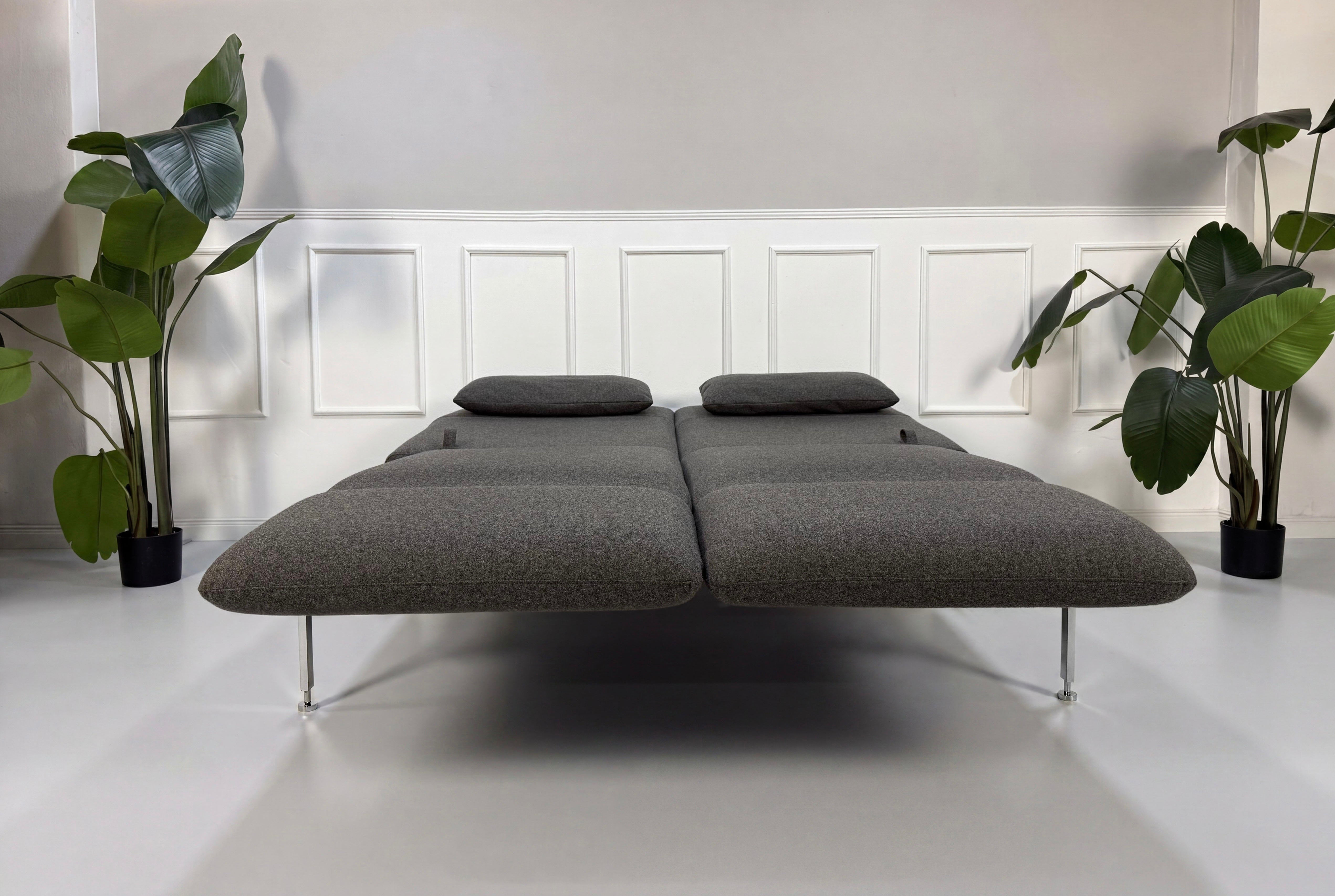 Gebrauchtes graues Brühl Roro Designer Stoff Sofa vor einer Wand, stilvoll und modern eingerichtet.