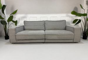 Gebrauchtes graues Bolia Noora Designer Stoff Sofa vor einer Wand, stilvoll und modern eingerichtet.