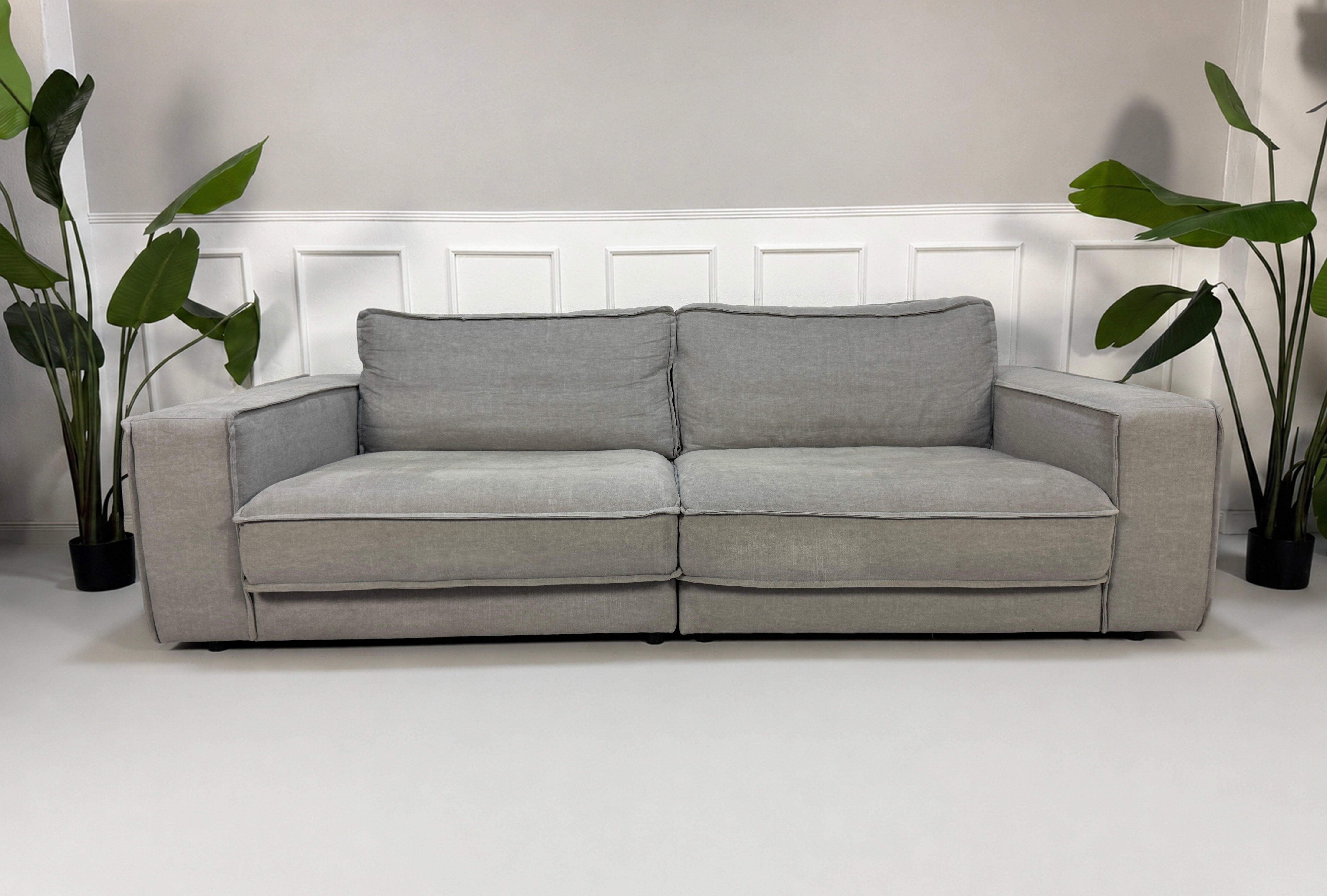 Gebrauchtes graues Bolia Noora Designer Stoff Sofa vor einer Wand, stilvoll und modern eingerichtet.