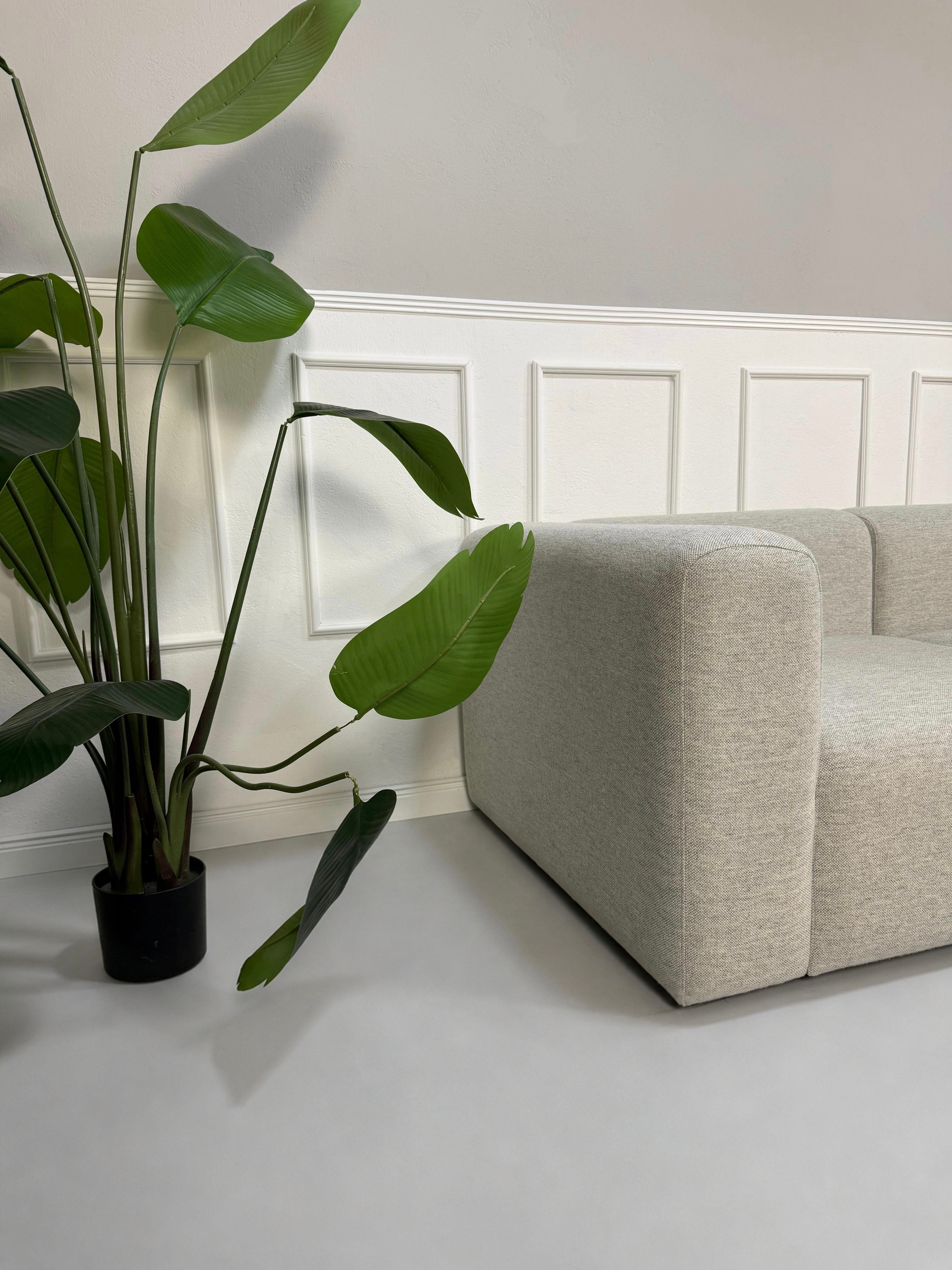 Gebrauchtes graues Hay Mags Designer Stoff Sofa vor einer Wand, stilvoll und modern eingerichtet.