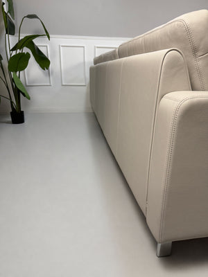 Gebrauchtes graues COR Conseta Designer Leder Sofa vor einer Wand, stilvoll und modern eingerichtet.