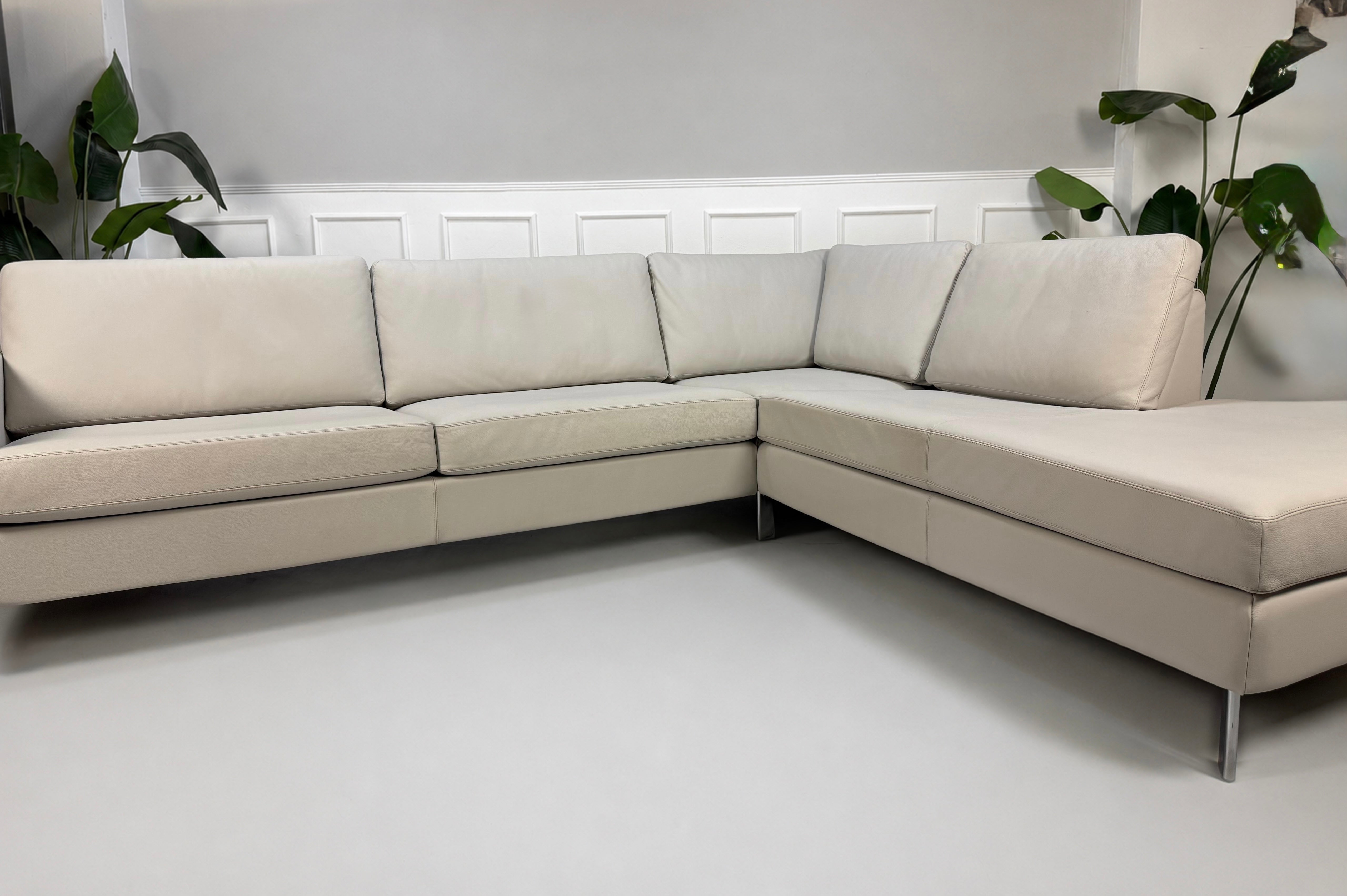 Gebrauchtes graues COR Conseta Designer Leder Sofa vor einer Wand, stilvoll und modern eingerichtet.
